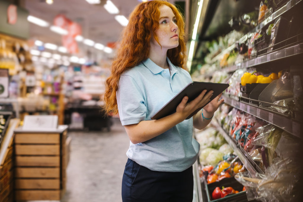 Female grocery store staff using technology to pick stock