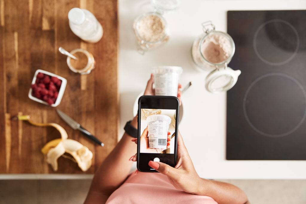 Woman using mobile app to scan yoghurt and add to shopping list